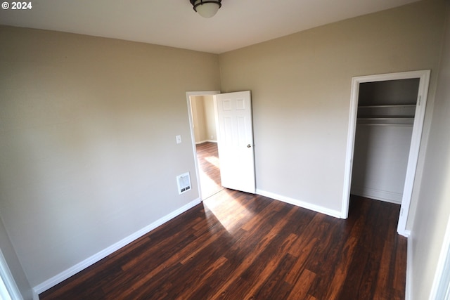 unfurnished bedroom with a closet and dark wood-type flooring