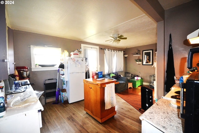 kitchen with ceiling fan, a center island, white refrigerator, white cabinets, and hardwood / wood-style flooring