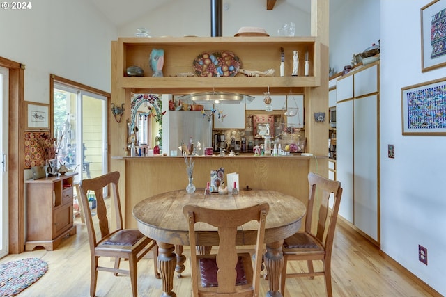 dining area featuring high vaulted ceiling and light hardwood / wood-style flooring