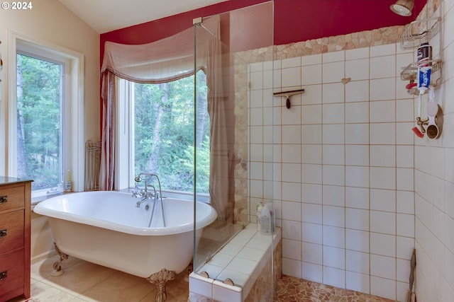 bathroom with shower with separate bathtub, tile walls, tile flooring, and a wealth of natural light