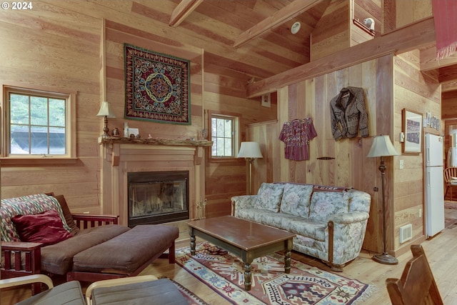 living room with wooden ceiling, wood walls, beam ceiling, and light hardwood / wood-style floors