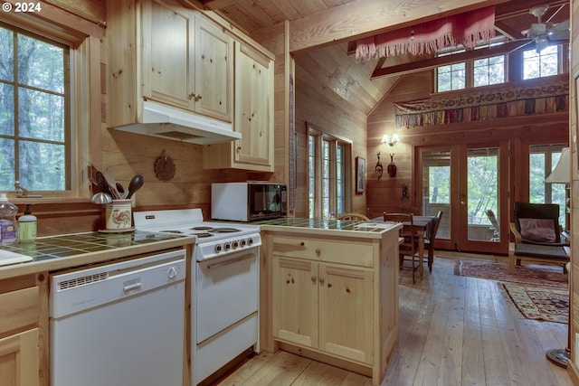 kitchen featuring ceiling fan, wooden walls, light hardwood / wood-style flooring, white appliances, and tile countertops