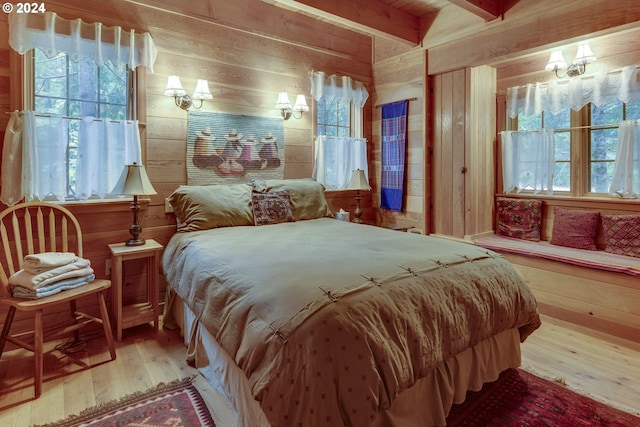 bedroom with light hardwood / wood-style flooring, beamed ceiling, and wooden walls