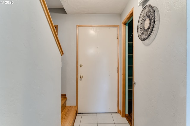 doorway with light tile patterned floors and a textured ceiling