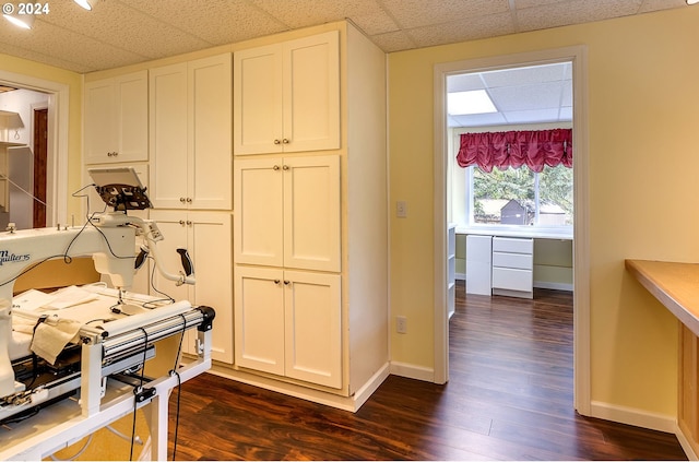 interior space with a paneled ceiling, dark wood-style flooring, and baseboards