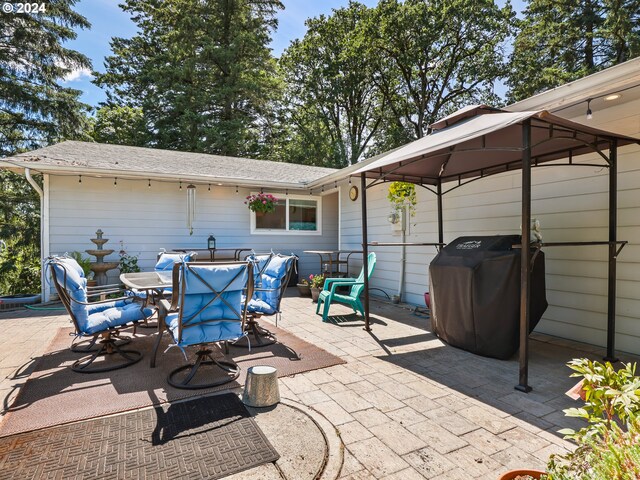 view of patio with area for grilling, a gazebo, and outdoor dining space
