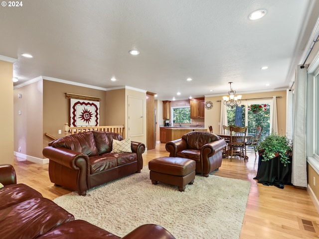 living room featuring crown molding, light hardwood / wood-style floors, and a notable chandelier