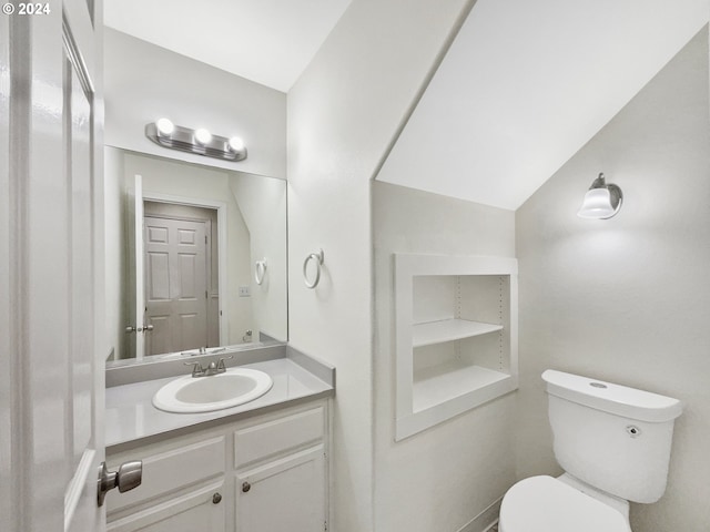 bathroom featuring vanity, lofted ceiling, and toilet