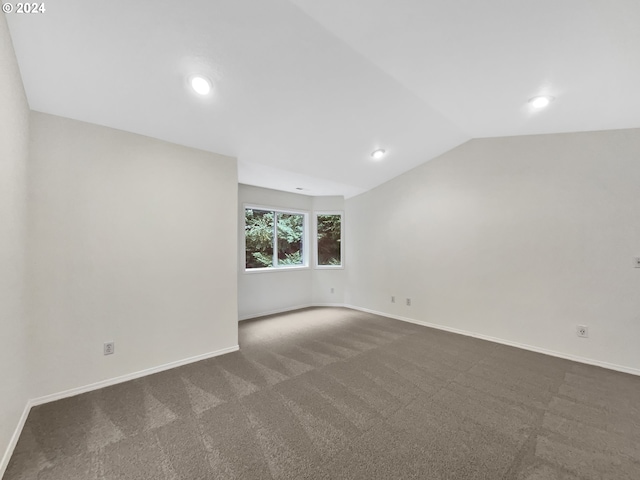 carpeted empty room with vaulted ceiling