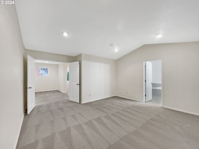 unfurnished room featuring light carpet and lofted ceiling