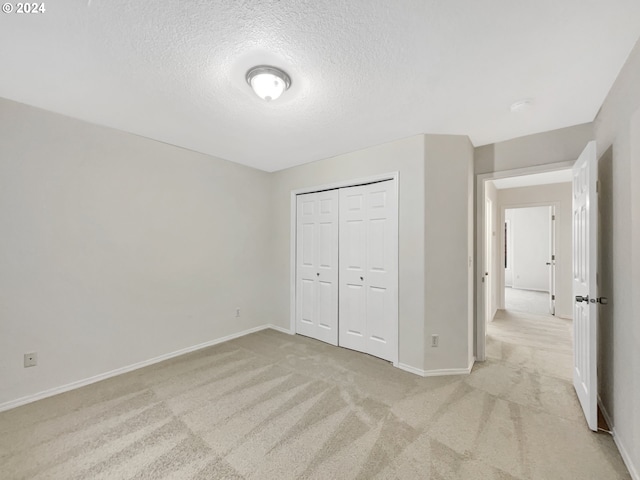 unfurnished bedroom with light carpet, a closet, and a textured ceiling