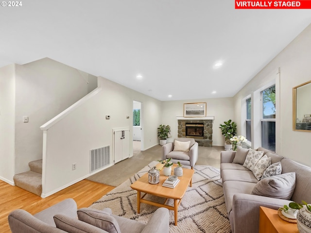 living room featuring a stone fireplace and light hardwood / wood-style floors