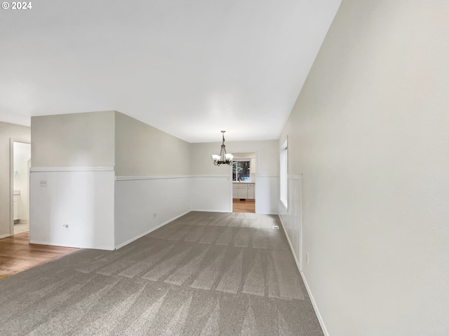 unfurnished living room with an inviting chandelier and carpet floors