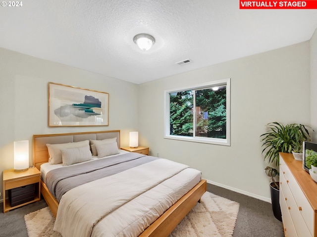 bedroom featuring a textured ceiling and dark colored carpet