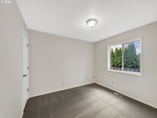 empty room with a textured ceiling and dark colored carpet