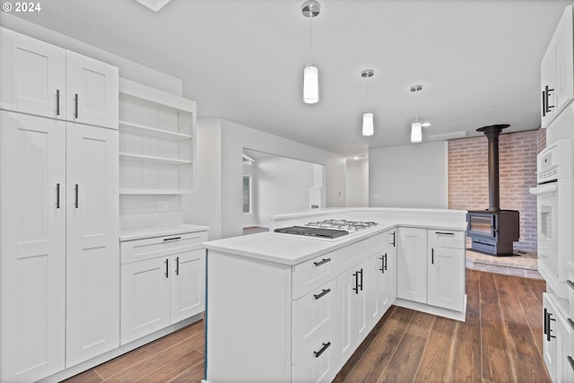 3735 NE Surf Dr, Lincoln City, OR 97367 - kitchen with white appliances, dark wood-style flooring, light countertops, a wood stove, and a kitchen island