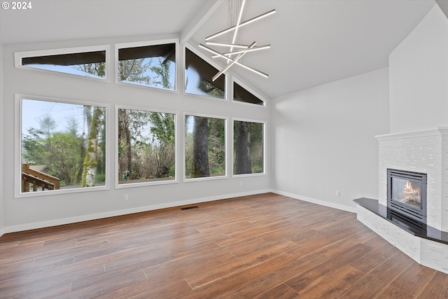 3735 NE Surf Dr, Lincoln City, OR 97367 - unfurnished living room featuring high vaulted ceiling, a glass covered fireplace, healthy amount of natural light, wood finished floors, and baseboards