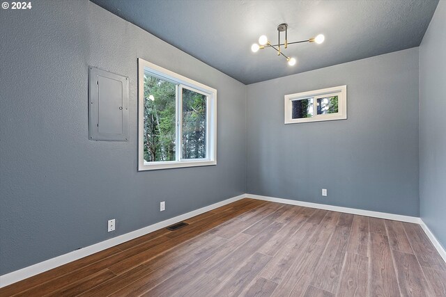 3735 NE Surf Dr, Lincoln City, OR 97367 - empty room with a chandelier, electric panel, wood finished floors, and baseboards