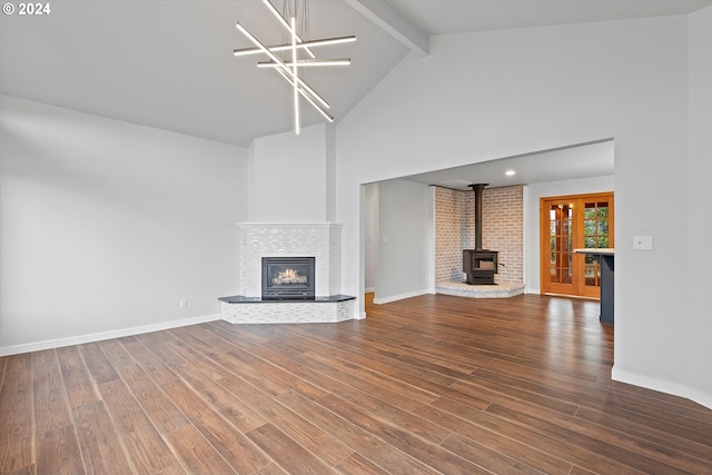 3735 NE Surf Dr, Lincoln City, OR 97367 - unfurnished living room featuring high vaulted ceiling, beam ceiling, a wood stove, wood finished floors, and baseboards