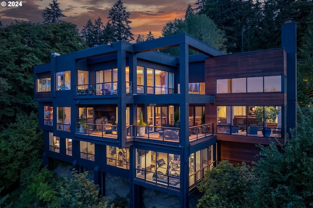 back house at dusk with a balcony