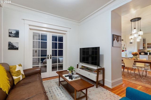 living room featuring crown molding, light hardwood / wood-style flooring, and french doors