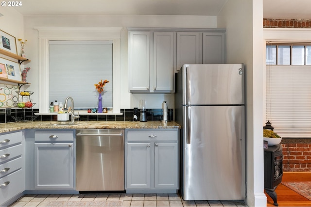 kitchen featuring stone counters, sink, stainless steel appliances, light hardwood / wood-style floors, and gray cabinets