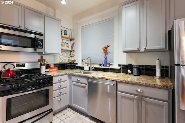 kitchen with light stone counters, gray cabinets, sink, and stainless steel appliances