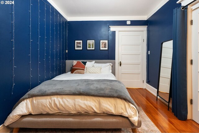 bedroom featuring ornamental molding and hardwood / wood-style flooring