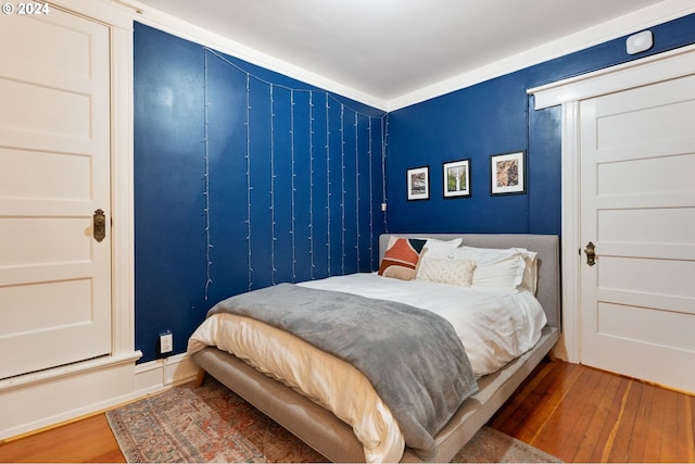 bedroom with crown molding and dark wood-type flooring