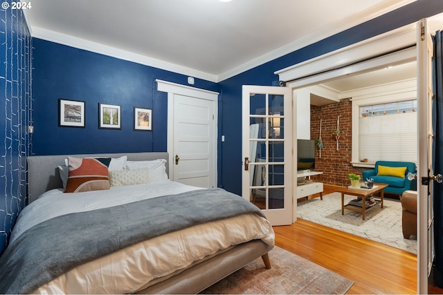 bedroom with hardwood / wood-style floors, crown molding, brick wall, and french doors