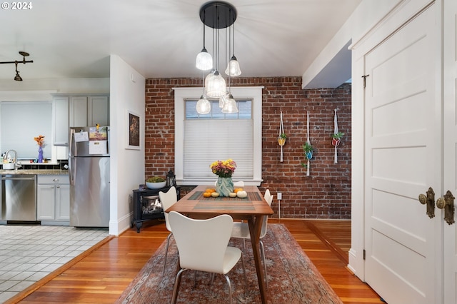 dining space featuring a notable chandelier, light wood-type flooring, and brick wall