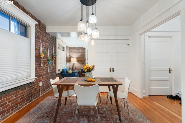 dining space with brick wall and wood-type flooring