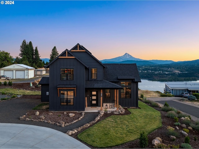 modern inspired farmhouse featuring a lawn, a garage, and a water and mountain view