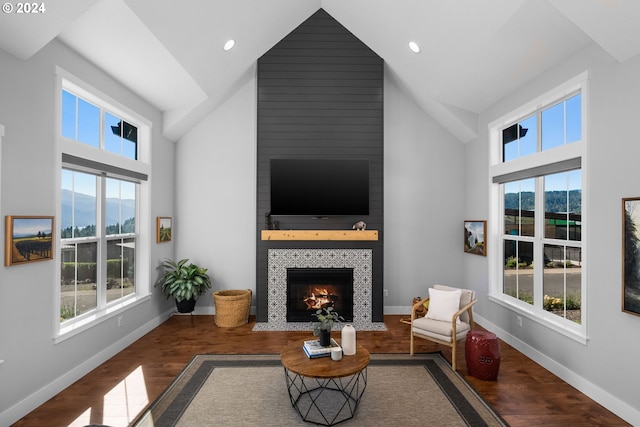 living room featuring hardwood / wood-style floors, high vaulted ceiling, a tile fireplace, and plenty of natural light