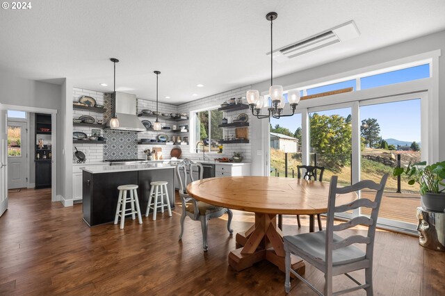 dining area featuring a textured ceiling, an inviting chandelier, sink, and dark hardwood / wood-style floors