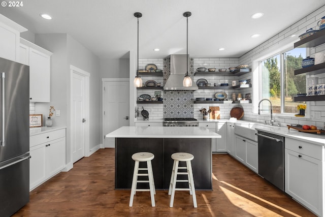 kitchen featuring a kitchen island, dark hardwood / wood-style floors, tasteful backsplash, stainless steel appliances, and wall chimney range hood