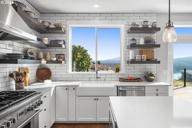 kitchen featuring white cabinets, hanging light fixtures, a mountain view, wall chimney exhaust hood, and tasteful backsplash