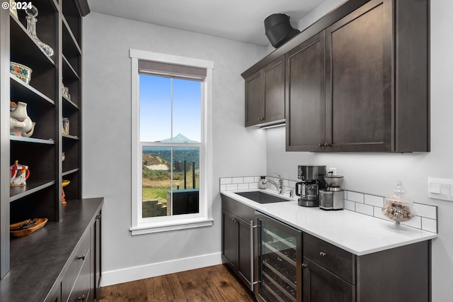 kitchen featuring dark hardwood / wood-style flooring, beverage cooler, dark brown cabinets, and sink