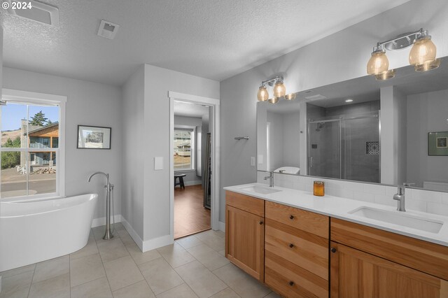 bathroom featuring tile patterned flooring, separate shower and tub, a textured ceiling, and vanity