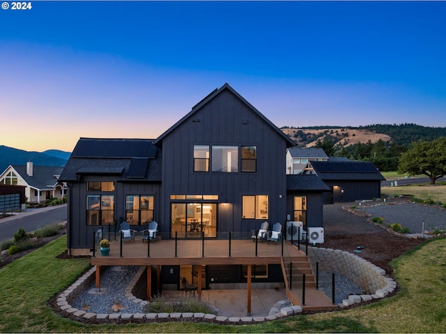 back house at dusk featuring a mountain view and a yard