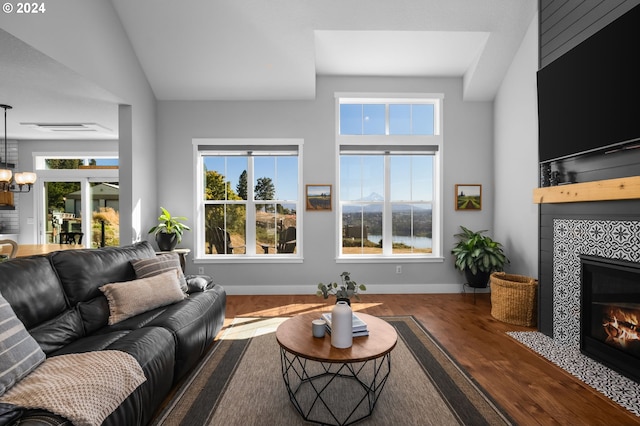 living room featuring hardwood / wood-style floors, a tile fireplace, an inviting chandelier, and vaulted ceiling