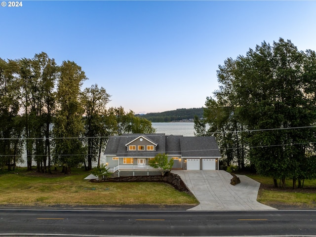 view of front of home with a front yard, a water view, and a garage