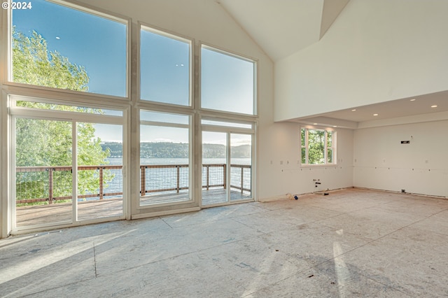 unfurnished living room featuring a water view and a high ceiling