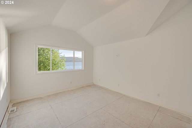 unfurnished room with a water view and vaulted ceiling