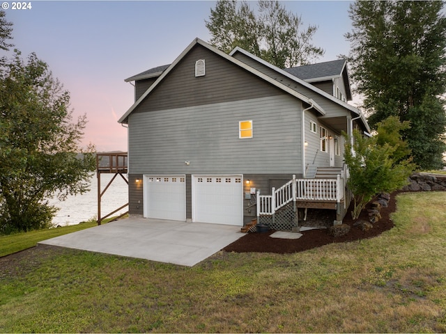 property exterior at dusk with a lawn and a garage