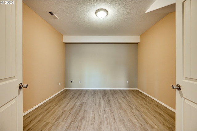 empty room with wood-type flooring and a textured ceiling