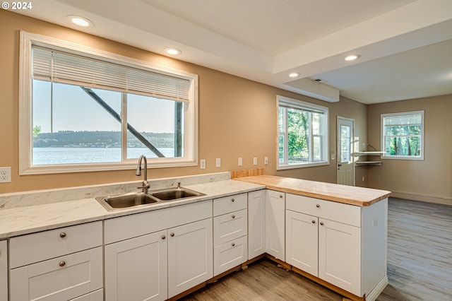 kitchen with white cabinetry, a water view, kitchen peninsula, and sink