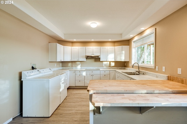 kitchen featuring sink, separate washer and dryer, kitchen peninsula, a breakfast bar area, and white cabinets