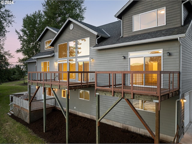 back house at dusk featuring a deck