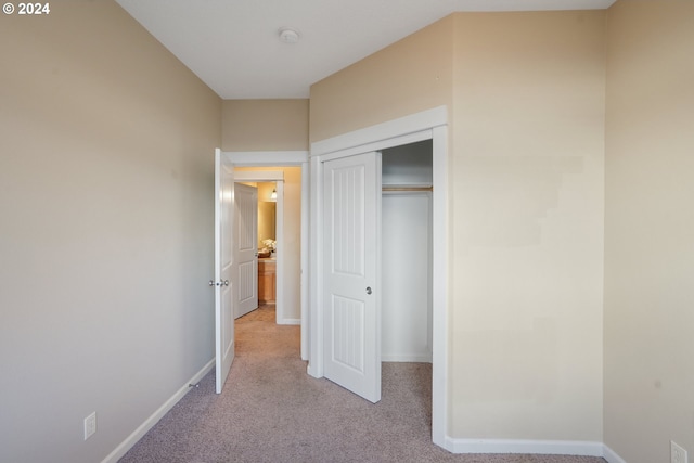 unfurnished bedroom featuring light carpet and a closet